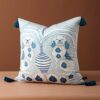 Velvet cushion pillow cover with organic light blue swirls, faded peach background, Victorian spaniel dogs, white-blue striped vase, and dark blue tassels