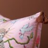 Pink velvet pillow cover with double-sided print of pink leopards, ceramic flower pot, white pigeons, butterflies, and rust tassels